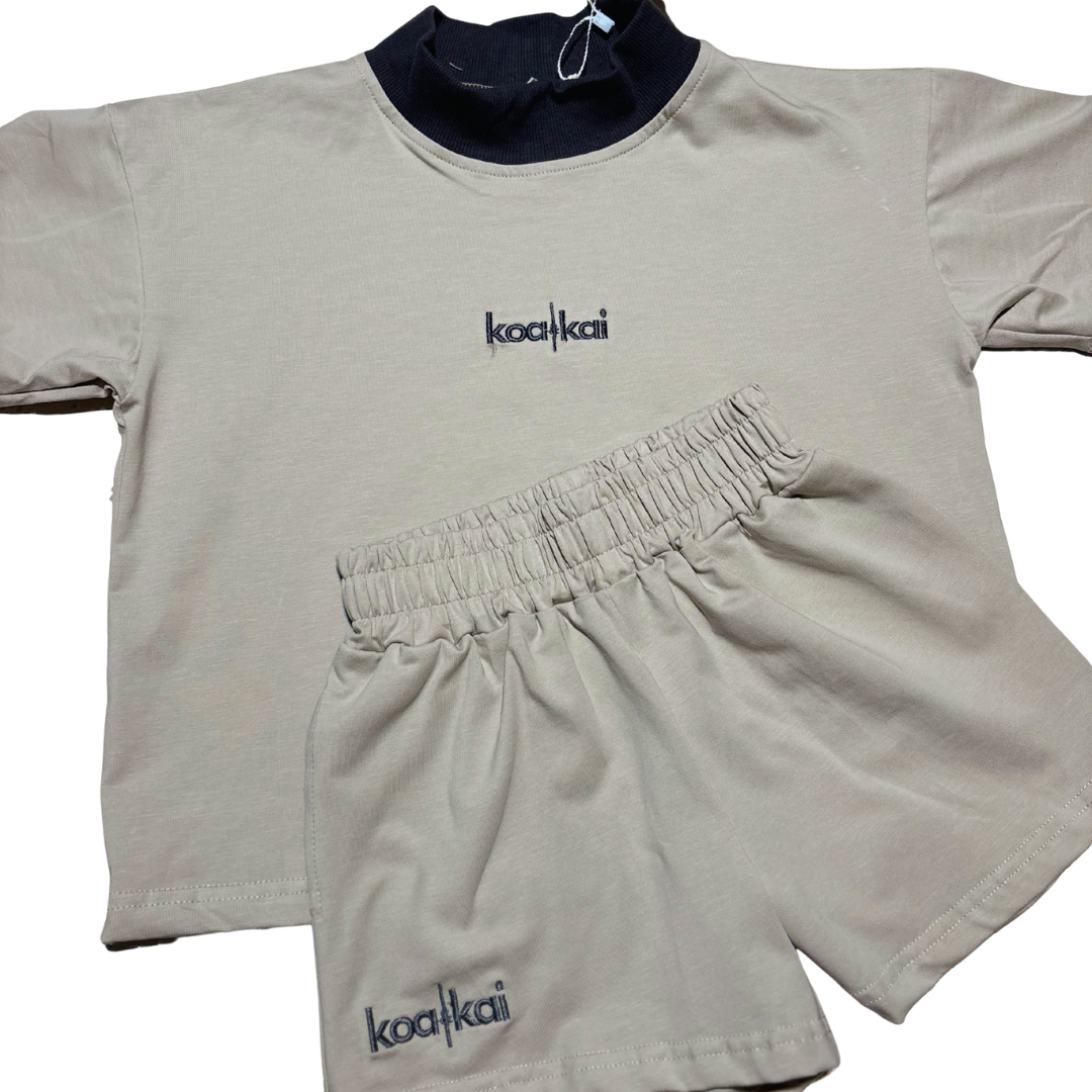 Beige athletic outfit with Dark grey collar and 'koakai' branding on a stone/beige background